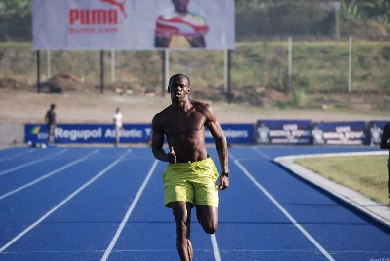 Usain Bolt cởi trần chạy trên đường đua.
