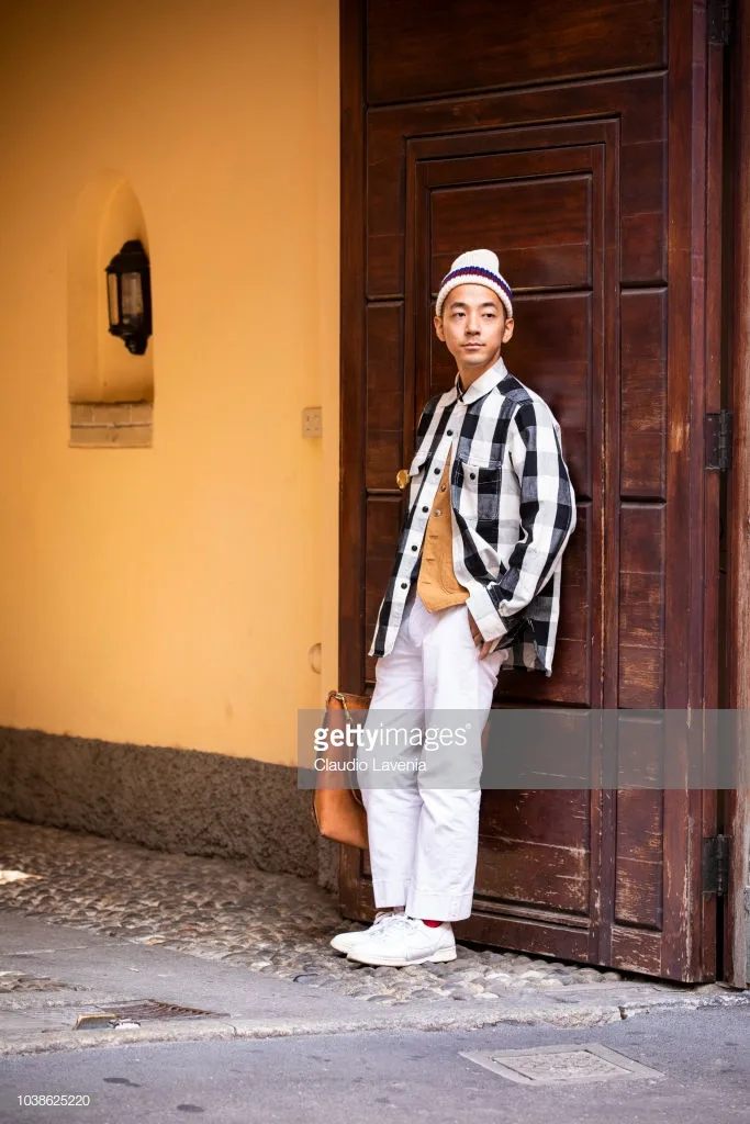 Sơ mi kẻ sọc bản to layer với áo phông cam tinh và mũ len tinh nghịch. Ảnh: Getty Images