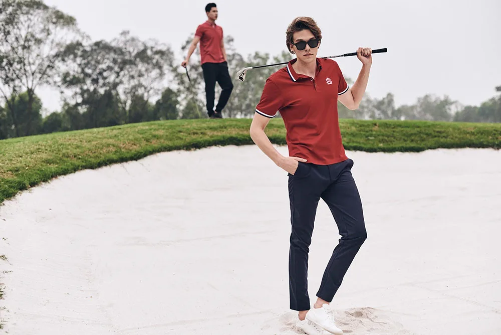 ao thun polo - chang trai mac ao polo cam dung trong ho cat cua san golf - elle man
