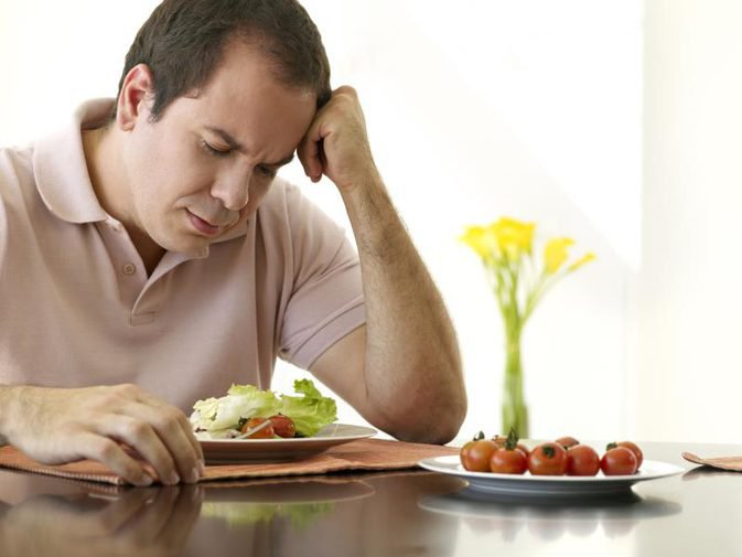 hình ảnh một người đàn ông mặc áo polo có triệu chứng chán ăn trước dĩa salad
