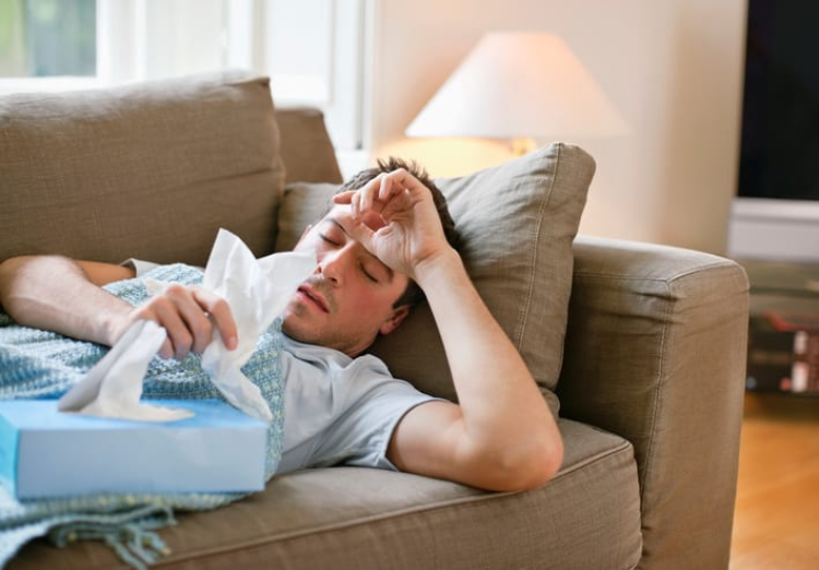 người đàn ông bị bệnh nằm trên ghế sofa.