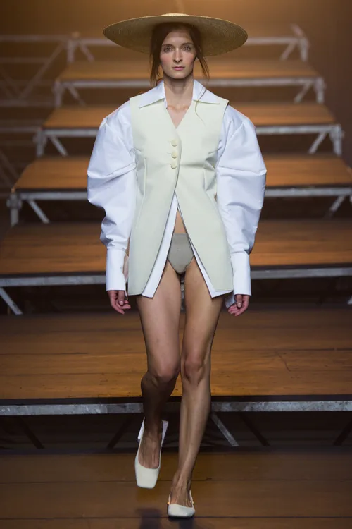 Simon Porte Jacquemus: người mẫu mặc áo sơ mi có tay áo trắng phồng dài, đội mũ cói.