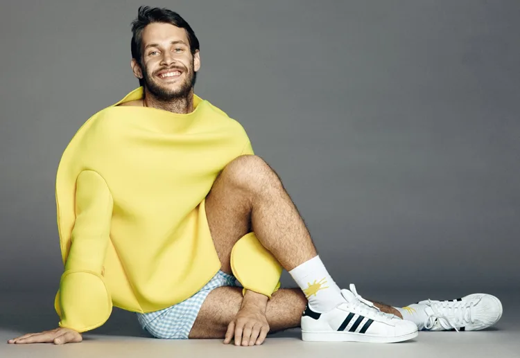 Simon Porte Jacquemus mặc áo vàng và ngồi bệt, chéo chân.