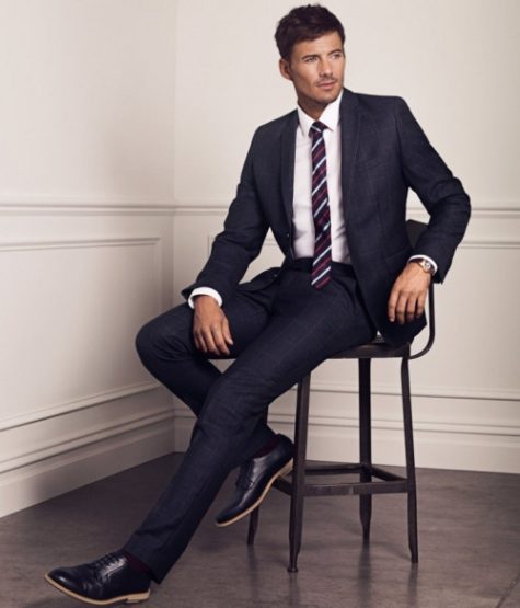9 điều về suit nam cần lưu ý: người mặc suit xanh navy, ngồi trên ghế.
