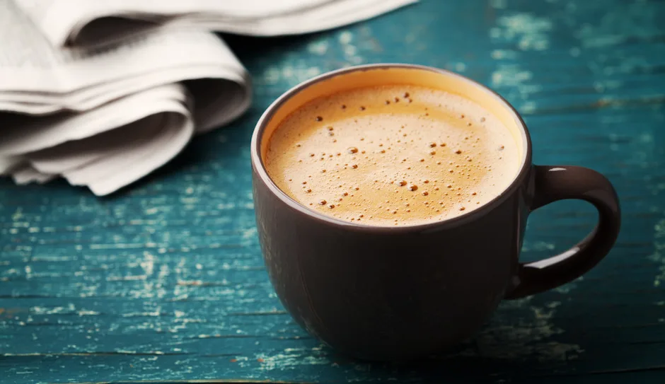 Coffee mug with newspaper on teal rustic table, cozy breakfast, vintage style