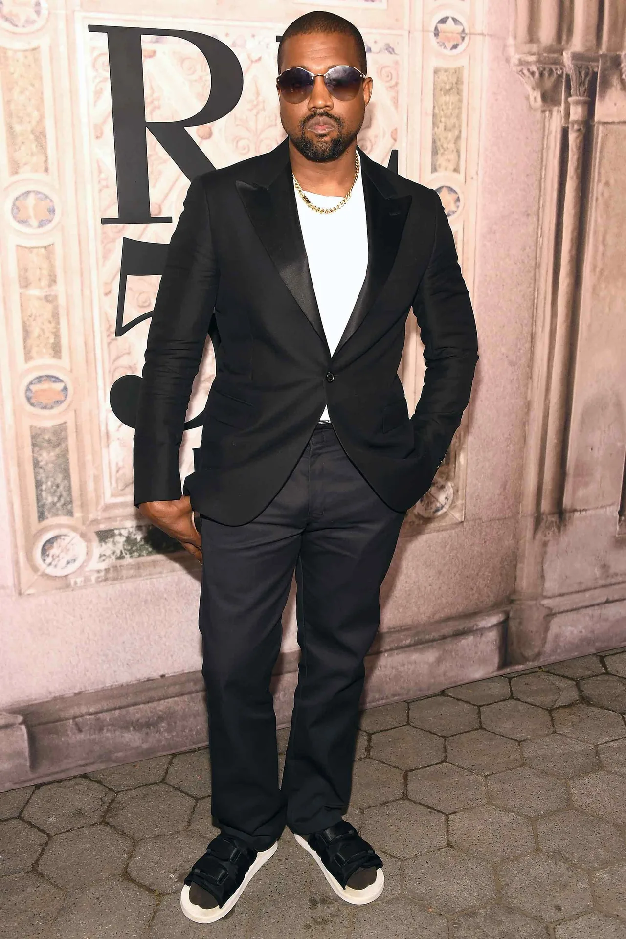 Kanye West gay ấn tượng khi phối bộ suit đen kinh điển cùng đôi dép lê đơn giản. Ảnh: GQ