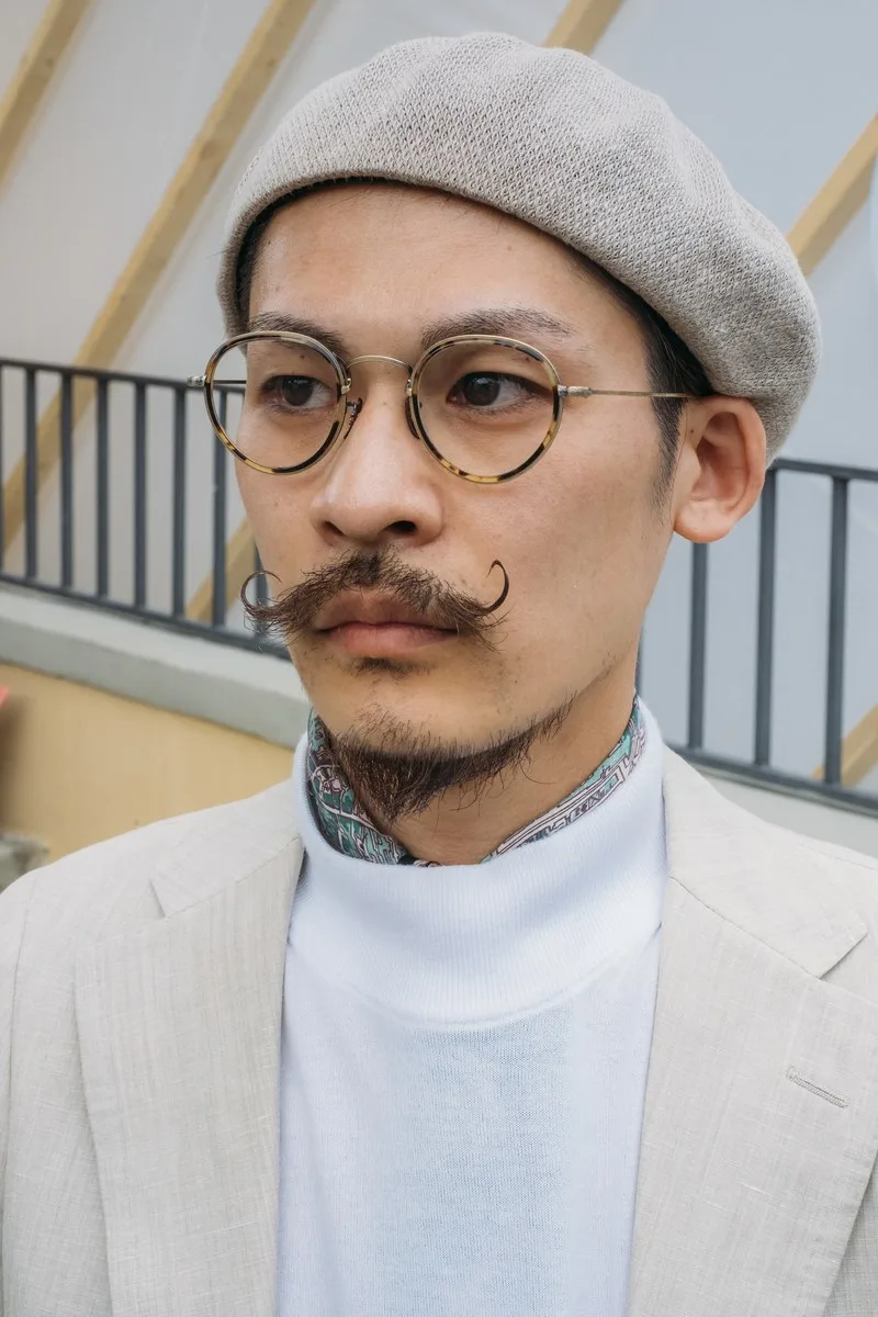 Chiếc mũ beret xám và chiếc kính tròn gọng mảnh càng tăng thêm vẻ nghệ sỹ cho chàng trai vớ bộ ria ấn ượng