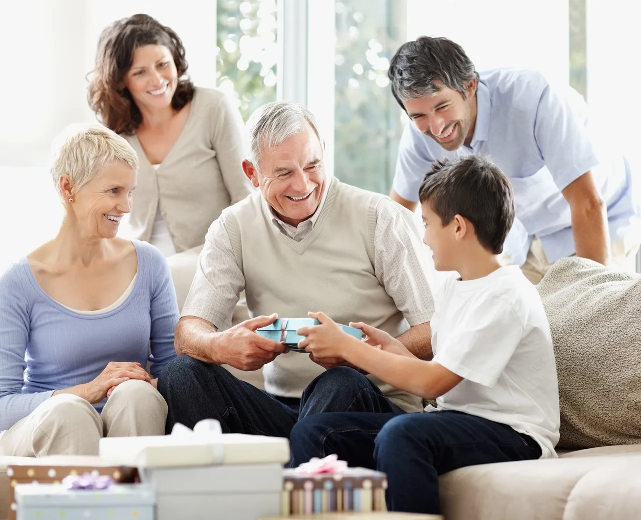 Happy family looking at an elderly man giving a gift his grandson